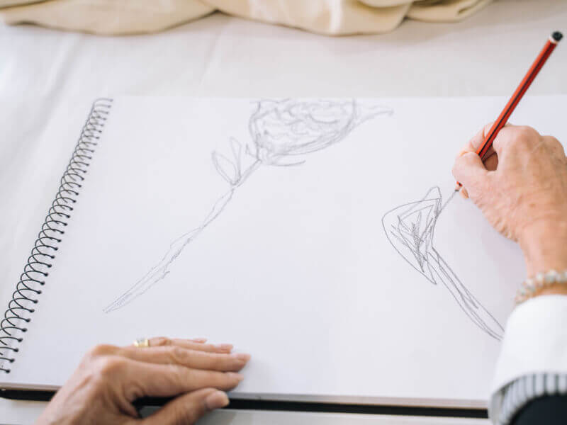 Hands holding a pencil sketching on paper in an art class